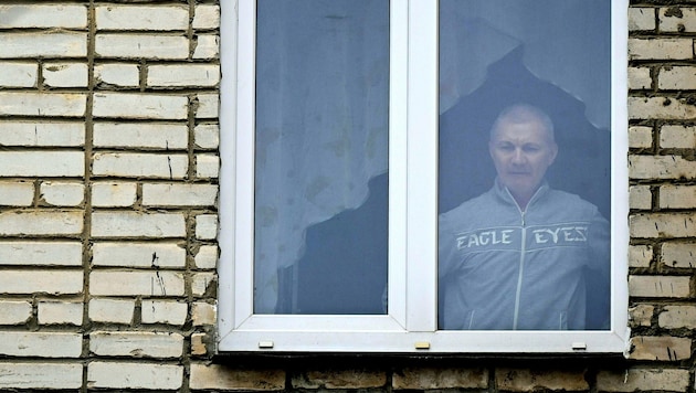 Dreary everyday life in Russia: Alexei Moskaljov looks out of his apartment. (Bild: APA/AFP/Natalia KOLESNIKOVA)