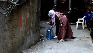 Palästinensische Flüchtlinge in Beirut füllen Trinkwasser in ihre mitgebrachten Behälter. (Bild: APA/AFP/JOSEPH EID)