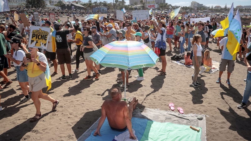 Keine Ruhe, keine Aussicht: Dieser Urlauber hat zwischen den Demonstranten am beliebten „Las Americas“-Strand auf Teneriffa wenig Spaß. (Bild: AFP)