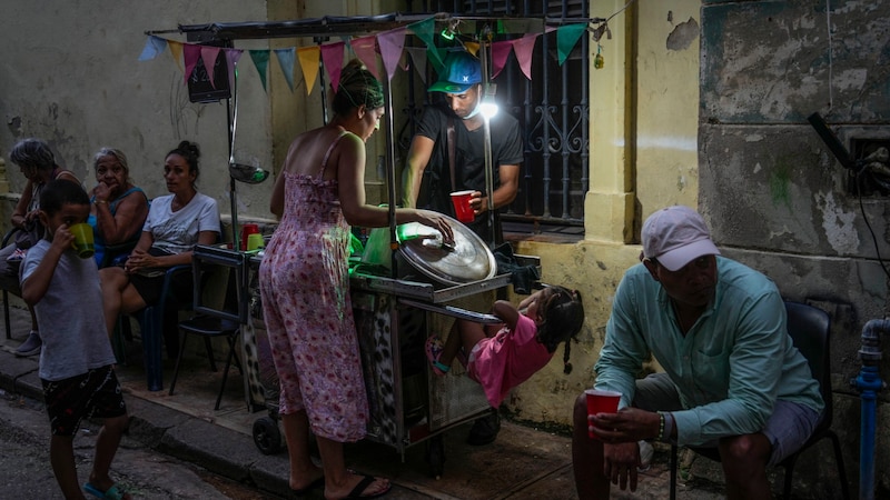 A street vendor goes about his business by the light of a flashlight. (Bild: APA/Associated Press)