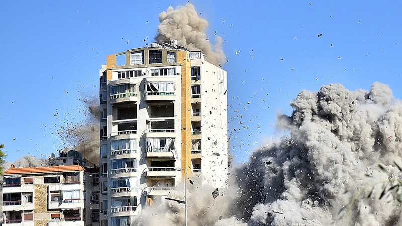 Zuerst kam die Evakuierungsaufforderung, wenig später wurde dieses Wohngebäude in Beirut dem Erdboden gleichgemacht. Ein AP-Fotoreporter hielt die Augenblicke fest. (Bild: APA/AFP)