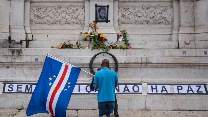 A man kneels in Lisbon in front of the picture of Odair Moniz, who died after a police ...