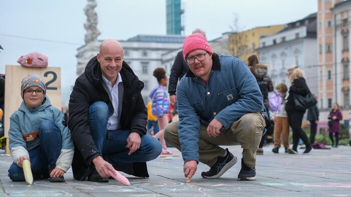 Martin Hajart mit Sohn Mathias und dem Künstler Clemens Bauder (re.) am Linzer Hauptplatz.