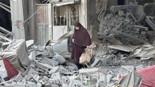 Eine Frau geht zwischen Trümmern in der Stadt Beit Lahiya im Norden des Gazastreifens. (Bild: APA/AFP)