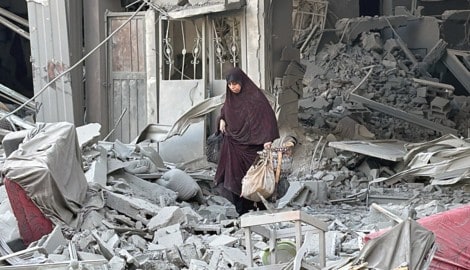 Eine Frau geht zwischen Trümmern in der Stadt Beit Lahiya im Norden des Gazastreifens. (Bild: APA/AFP)