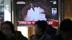 Passanten beobachten mit Sorge Aufnahmen des Raketenstarts auf einen Bildschirm in Seoul. (Bild: APA/AFP/JUNG YEON-JE)