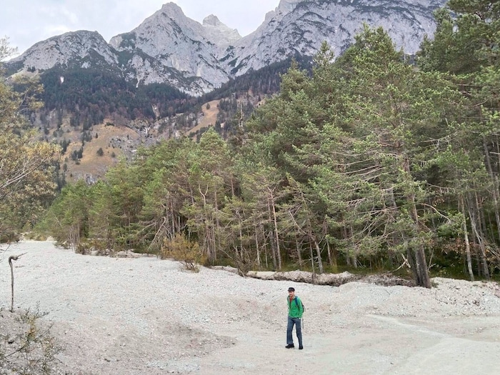 Zweimal wird vor dem Hintergrund der Karwendelberge ein ausgetrocknetes Bachbett überquert – hier jenes des Fallbachs.