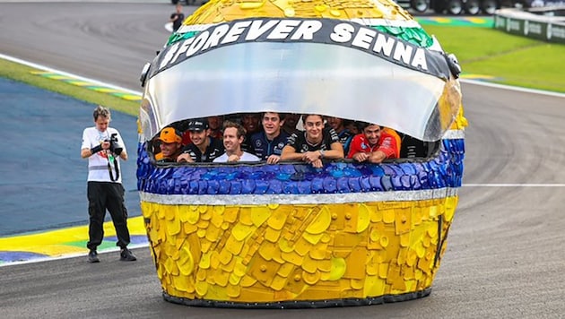 Sebastian Vettel with the Formula 1 drivers in a giant Senna helmet made from garbage (Bild: x.com/F1)