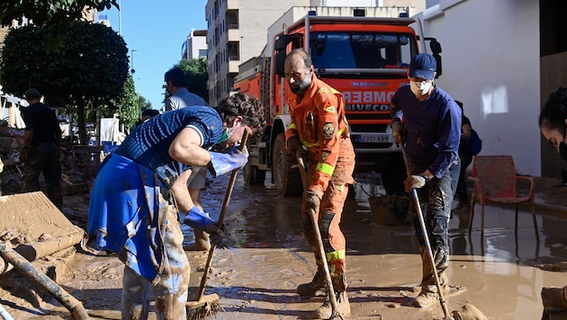 Volunteers and Spain's fire department clear a road of mud. (Bild: AFP/Jose Jordan)