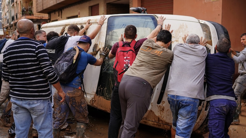 Menschen versuchen, ein Auto aus dem Schlamm zu ziehen. (Bild: AFP/Manaure Quintero)