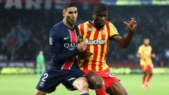 PSG star Achraf Hakimi in a duel with Austrian Lens defender Kevin Danso (Bild: AFP)