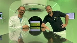 Im Bunker und vor dem Gerät zur Strahlentherapie: Medizinphysiker Christoph Gaisberger (li.) und Radiologie-Technologe Philipp Scherer. (Bild: Maximilian Kronberger)