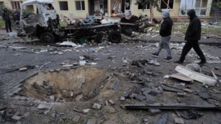 Die Lage am Samstag in Odessa: Ein großer Krater unterbricht die Straße, Autos sind ausgebrannt. (Bild: APA/AFP/Oleksandr GIMANOV)