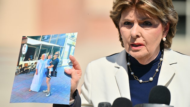 Gloria Allred, Anwältin der Familie von Halyna Hutchins, hält ein Foto von Hutchins  hoch, auf dem sie ihren Sohn Andros im Arm hält, während sie neben ihrer Mutter Olga Solovey steht. (Bild: APA Pool/Getty Images via AFP/GETTY IMAGES/Sam Wasson)