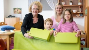 Familien-Landesrätin Christiane Teschl-Hofmeister und Pädagogin Carina Kerschner imitieren mit Simon Effenberger und Josephine Grießler mit Schaumstoffpolster einen Hochwasserschutz. (Bild: NLK Pfeffer)