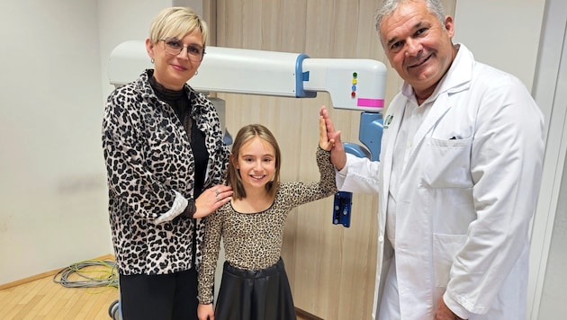 Noemi mit Mama Bianka und dem Chef der Kinder- und Jugendchirurgie, Holger Till vor dem Roboter. (Bild: Christa Blümel)