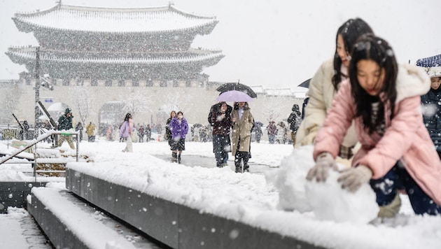 Building a snowman in the center of Seoul. (Bild: APA/AFP/ANTHONY WALLACE)