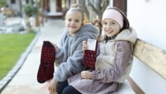 Helena (li.) und Gioia mit den „Funken Wärme“-Socken, die man im „Schenken mit Sinn“-Shop erwerben kann. Der Erlös kommt unserer Hilfsaktion zugute. (Bild: Reinhard Holl)