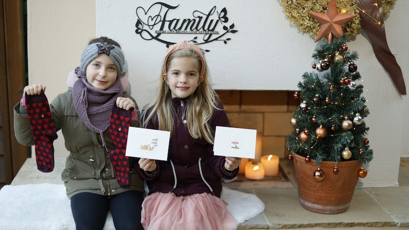 Gioia (li.) und Helena mit Billets und „Funken Wärme“-Socken, die man im „Schenken mit Sinn“-Shop erstehen kann. (Bild: Reinhard Holl)