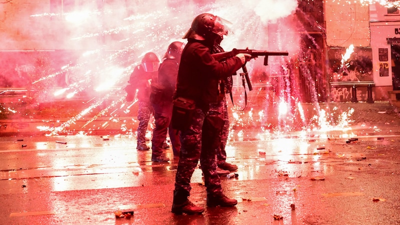 Demonstranten schießen Feuerwerkskörper auf Polizisten, die Tränengas abfeuern. (Bild: APA/AFP/Giorgi ARJEVANIDZE)