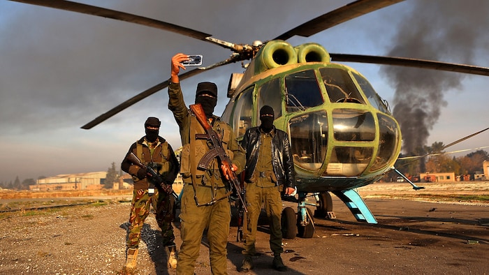 Rebellen posieren für ein Selfie vor einem in Aleppo erbeuteten Armeehubschrauber.