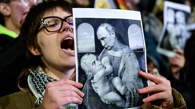 Protest gegen Calin Georgescu, der auf einem verfremdeten Bild von Leonardo Da Vincis „Madonna mit Kind“ als Kind von Kremlchef Wladimir Putin abgebildet wird. (Bild: APA/AFP/Daniel MIHAILESCU)