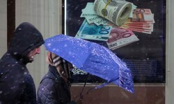Es weht ein rauer Wind. Fußgänger marschieren in Sankt Petersburg an einer Wechselstube vorbei.