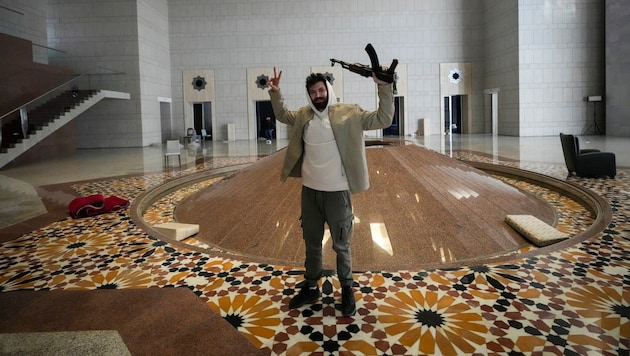 A rebel fighter poses in Bashar al-Assad's palace in Damascus. (Bild: AP)