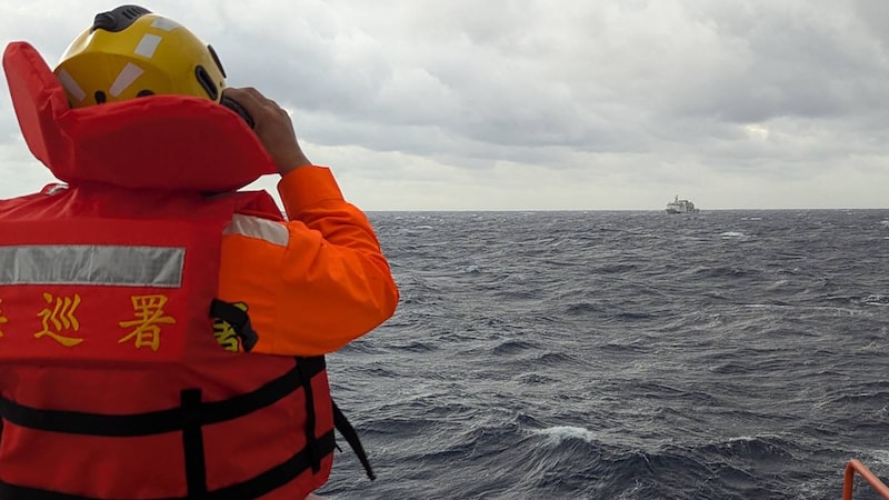 A crew member on board a Taiwanese coast guard vessel observes a Chinese coast guard vessel. (Bild: APA/AFP/TAIWAN COAST GUARD/Handout)