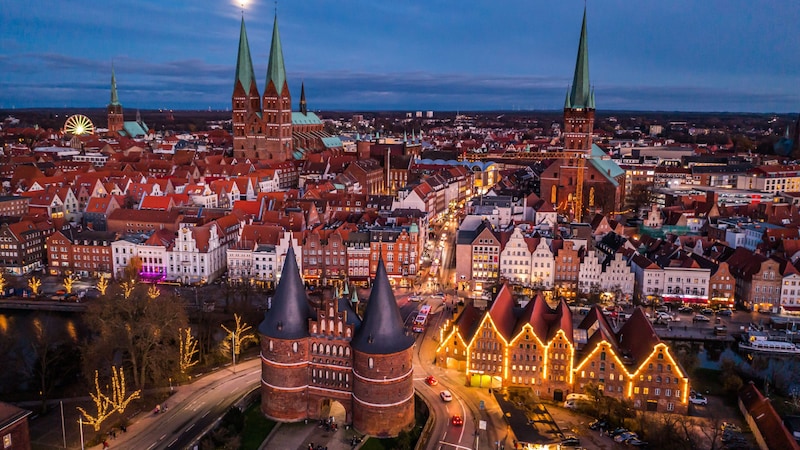 Panoramablick auf das weihnachtliche Lübeck mit seinen Kirchtürmen und das Holstentor (vorne) mit seinen wuchtigen Doppeltürmen. (Bild: LTM)