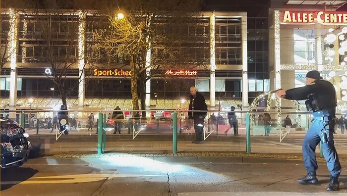 Ein Polizist nähert sich während der Verhaftung mit gezogener Waffe dem am Boden liegenden ...