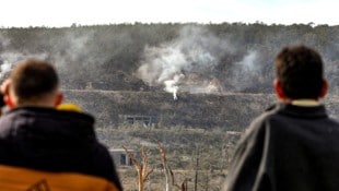 Syrische Zivilisten beobachten den Schauplatz eines israelischen Luftschlags, wo noch Rauch aufsteigt. (Bild: APA/AFP/Bakr ALKASEM)