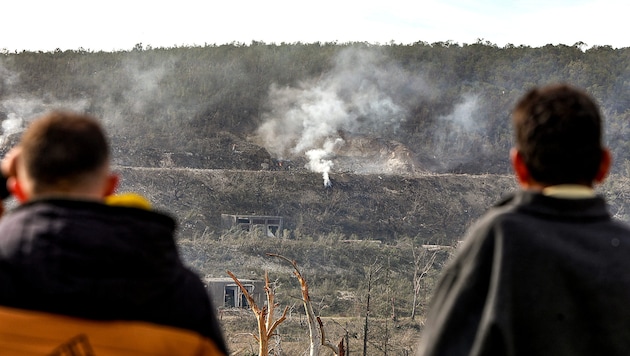 Syrische Zivilisten beobachten den Schauplatz eines israelischen Luftschlags, wo noch Rauch aufsteigt. (Bild: APA/AFP/Bakr ALKASEM)