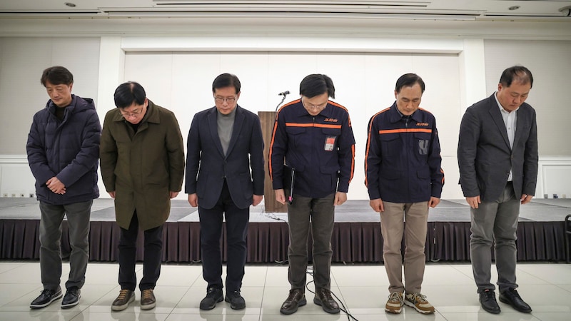 Die CEO von Jeju Air, Kim E-bae (4.v.li.), und weitere Mitglieder der Führungsriege verbeugen sich vor einer Pressekonferenz als Zeichen ihrer Entschuldigung. (Bild: APA/Yonhap)