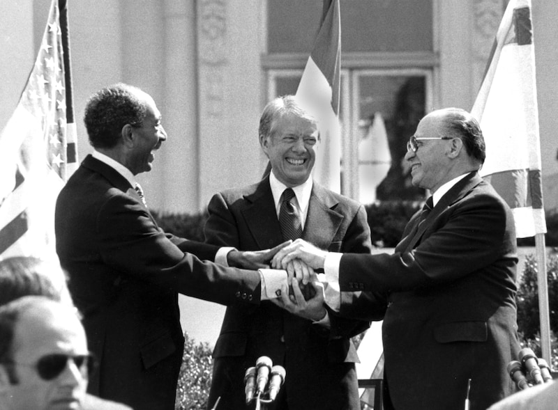 In Camp David, Israel and Egypt sign an agreement under Carter's mediation that leads to a peace treaty between the two states. In the picture: Jimmy Carter with Israel's Prime Minister Menachem Begin (right) and Egypt's Anwar Sadat (left) on March 26, 1979 (Bild: AP)