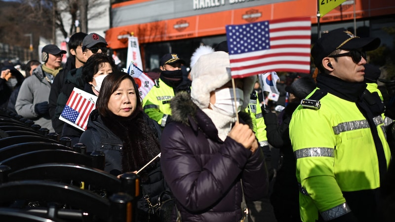 Unterstützer des Präsidenten protestieren gegen die Festnahmeanordnung und schwenken dabei US-Flaggen. (Bild: APA/AFP)