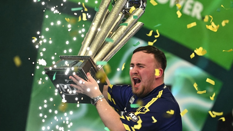 Luke Littler mit seiner WM-Trophäe (Bild: APA/AFP/Ben STANSALL)