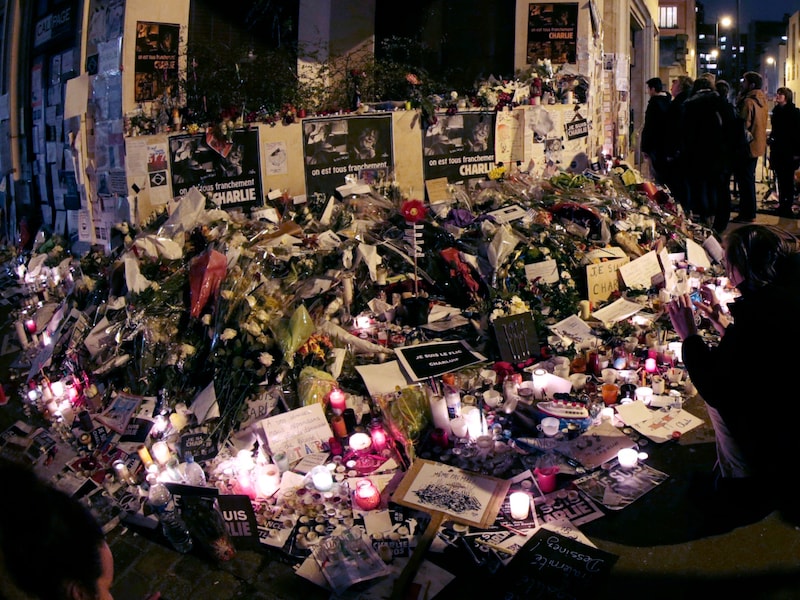 Am 11. Jänner 2015, am Ende der Einheitsdemonstration „Marche Républicaine“ in Paris, versammelten sich Menschen an einer provisorischen Gedenkstätte in der Nähe des Hauptsitzes der Satirezeitschrift „Charlie Hebdo“. (Bild: APA/AFP/Joël SAGET)