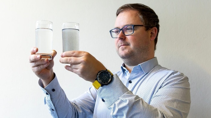 Forscher Paul Zabel begutachtet zwei Proben des aus Regolith extrahierten Wassers (links das mit ...