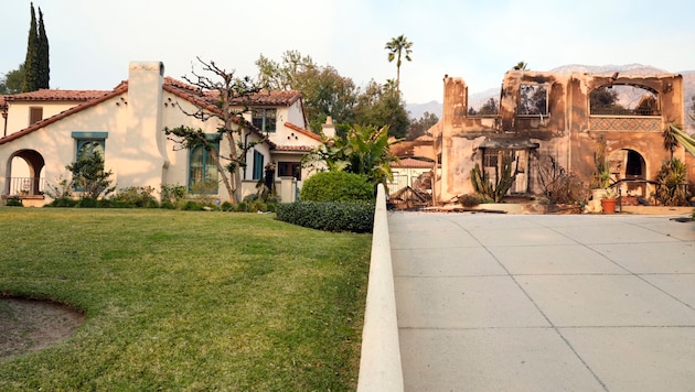 Das aus der Fernsehserie „Beverly Hills 90210“ bekannte Walsh-Haus steht unbeschädigt neben einem Haus, das durch das Eaton-Feuer in Altadena, Kalifornien, zerstört wurde. (Bild: AP/Chris Pizzello)