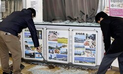 Angestellte kehren Glasscherben einer zerbrochenen Schaufensterscheibe am Flughafen von Miyazaki ...