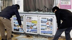 Angestellte kehren Glasscherben einer zerbrochenen Schaufensterscheibe am Flughafen von Miyazaki ...