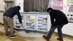 Angestellte kehren Glasscherben einer zerbrochenen Schaufensterscheibe am Flughafen von Miyazaki zusammen. (Bild: APA/AP)