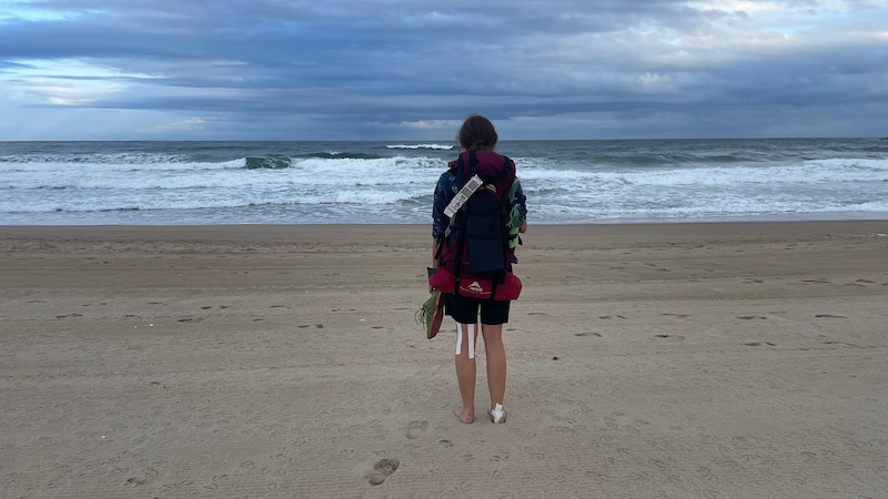 Rita M. an einem Strand in Spanien. Da hatte sie das Zelt noch im Gepäck (unten am Rucksack rot). (Bild: Rita M.)