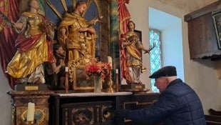 Pfarrer Friedrich Isop präsentiert die Reliquien: Ein Handschuh im goldenen Rahmen vor der Hildegard-Statue, ein Kopfschmuck und das Gebiss der Hildegard von Stein sind am Seitenaltar aufbewahrt. (Bild: Christina Natascha Kogler)