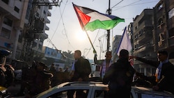 Ein Mann im Gazastreifen schwenkt die palästinische Flagge, um die Waffenruhe zu feiern – zu früh, wie am Sonntagmorgen bekannt wurde.  (Bild: APA/AFP)