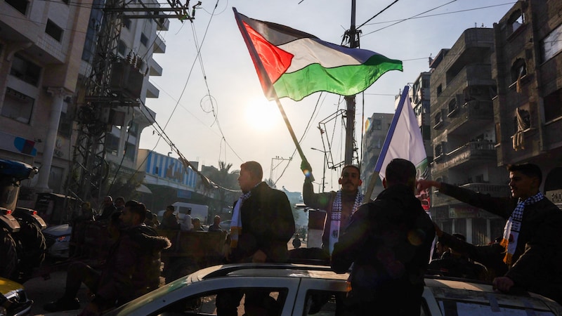 Ein Mann im Gazastreifen schwenkt die palästinische Flagge, um die Waffenruhe zu feiern – zu früh, wie am Sonntagmorgen bekannt wurde. (Bild: APA/AFP)