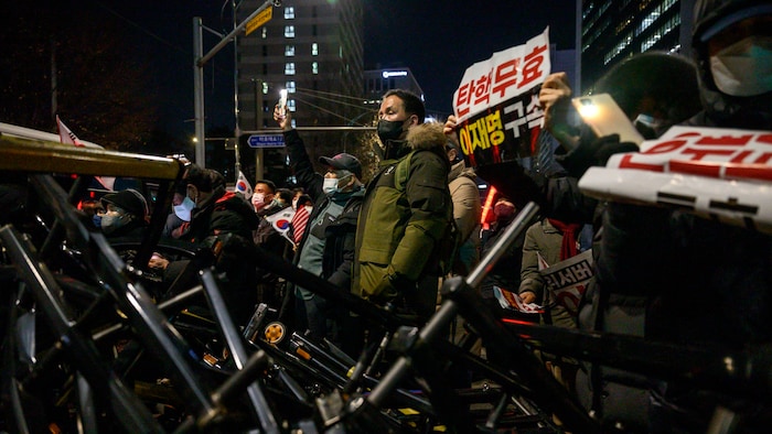 A protester stands on overturned police barricades.