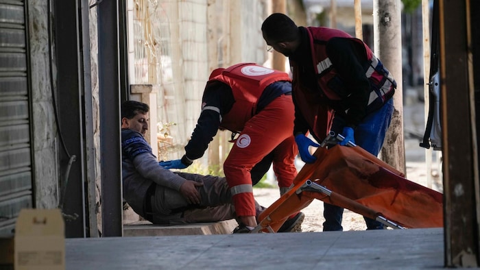 Red Crescent workers carry a wounded man to safety in Jenin.