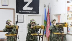 „Übung“ mitten im Klassenzimmer. Das „Z“ ist ein russisches Militärzeichen und ein Symbol für die Unterstützung des Angriffskrieges. Darunter steht: „Wir lassen die Unseren nicht im Stich.“  (Bild: Илья Наймушин / Спутник / РИА Новости / Profimedia)